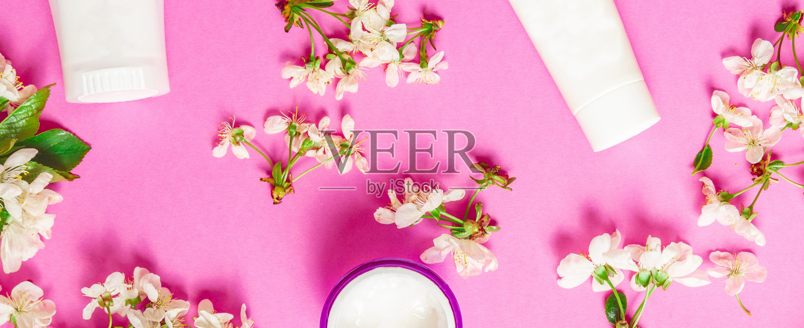 装饰化妆品产品和鲜花在粉红色的背景。春季化妆品销售横幅。美容院宣传横幅。照片摄影图片