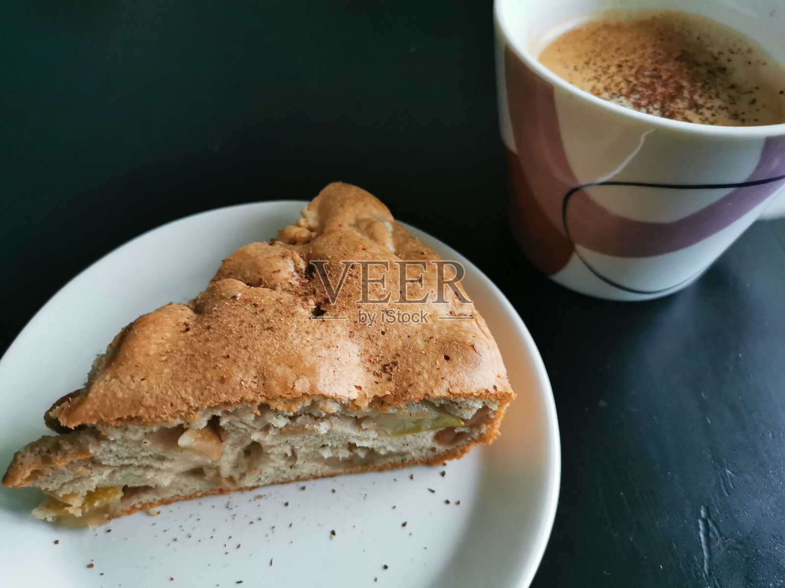 在白色茶托和一杯咖啡上撒上肉桂和香料的一块夏洛特(苹果派)照片摄影图片