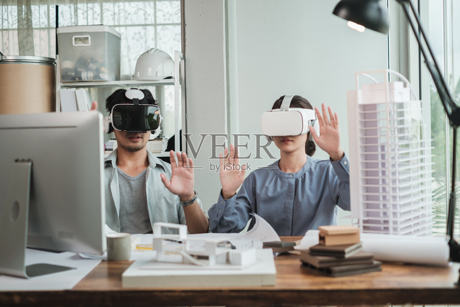 建筑师戴着虚拟现实耳机详细项目房屋模型。照片摄影图片