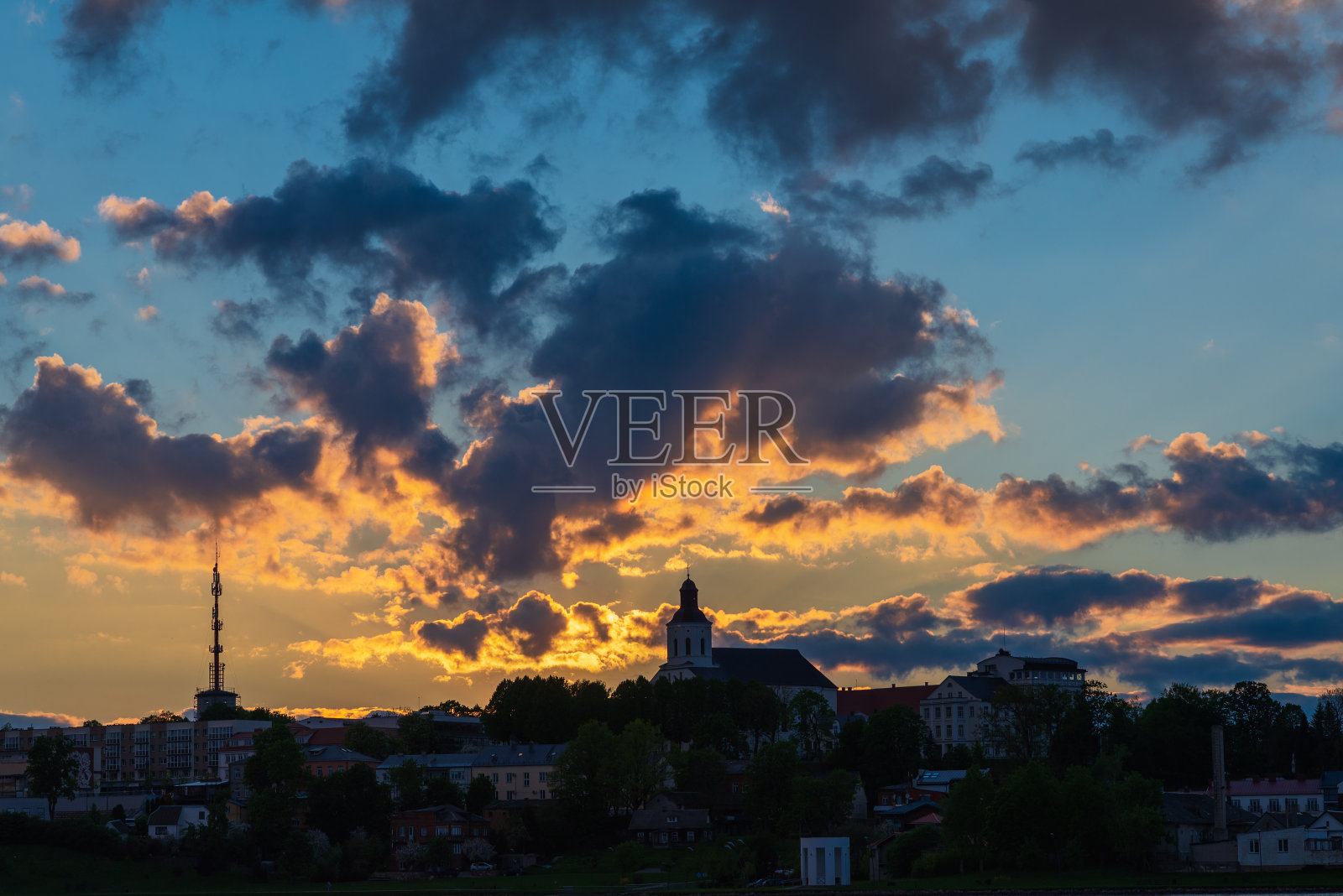 城镇的海岸在夕阳下。阳光穿过乌云笼罩着湖湾小镇。城市形象。照片摄影图片