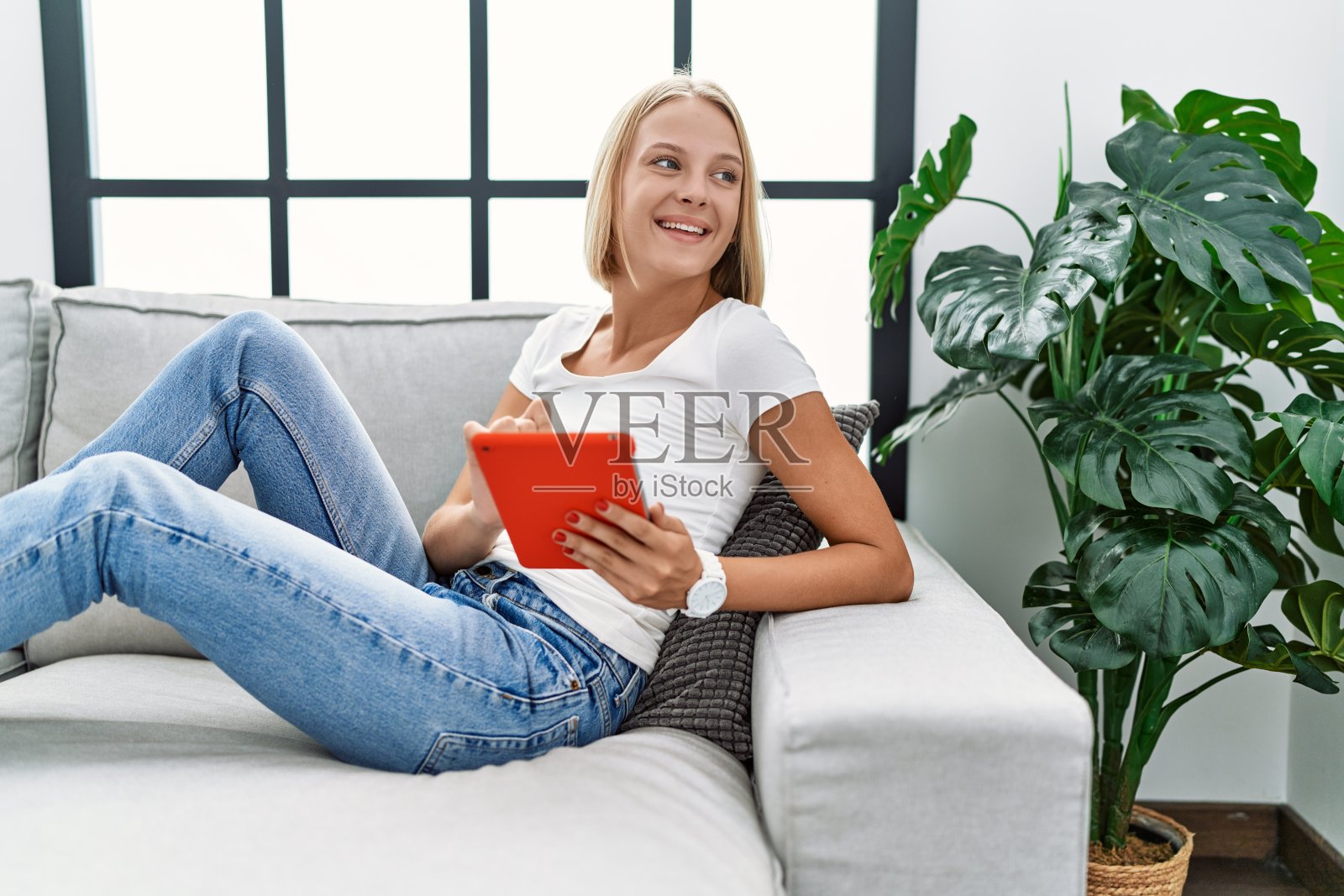 年轻的金发女人在家里用触控板微笑自信照片摄影图片