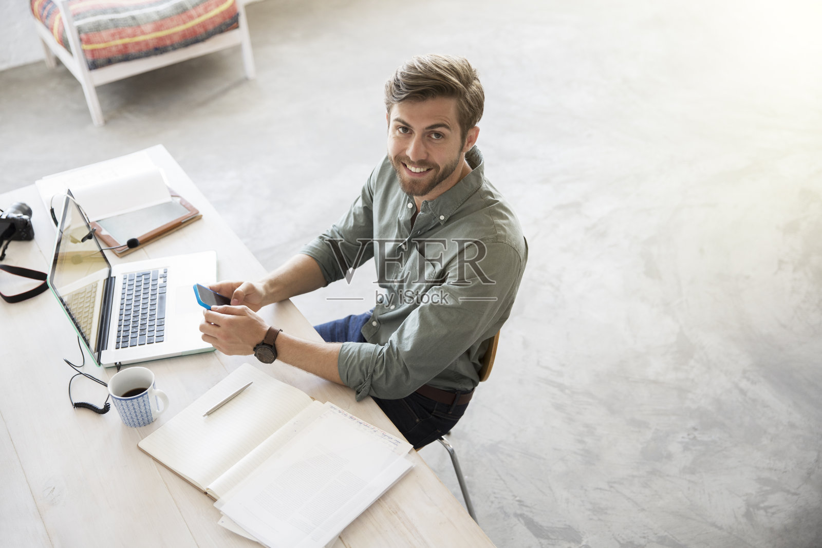 年轻男子的肖像坐在桌子上的移动电话和笔记本电脑照片摄影图片