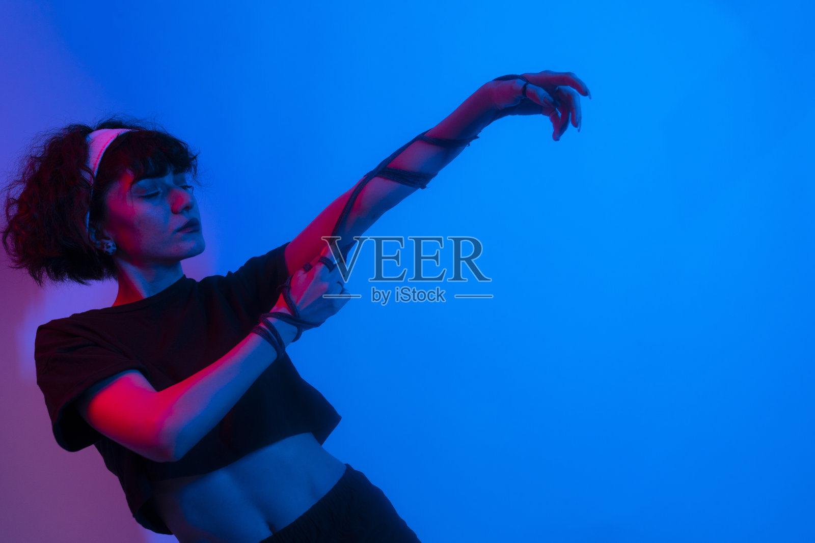 一个时尚的年轻女孩的肖像,酷的舞蹈和发展的头发,霓虹灯背景。高质量的照片照片摄影图片