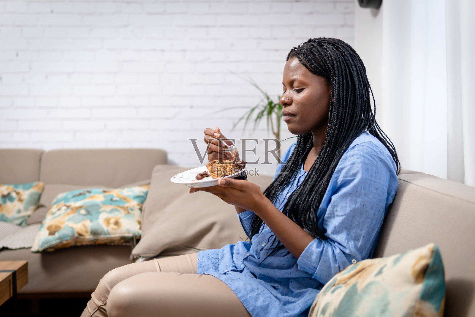 漂亮的女孩喜欢吃巧克力蛋糕。一个漂亮的年轻女人在吃一块甜蛋糕照片摄影图片