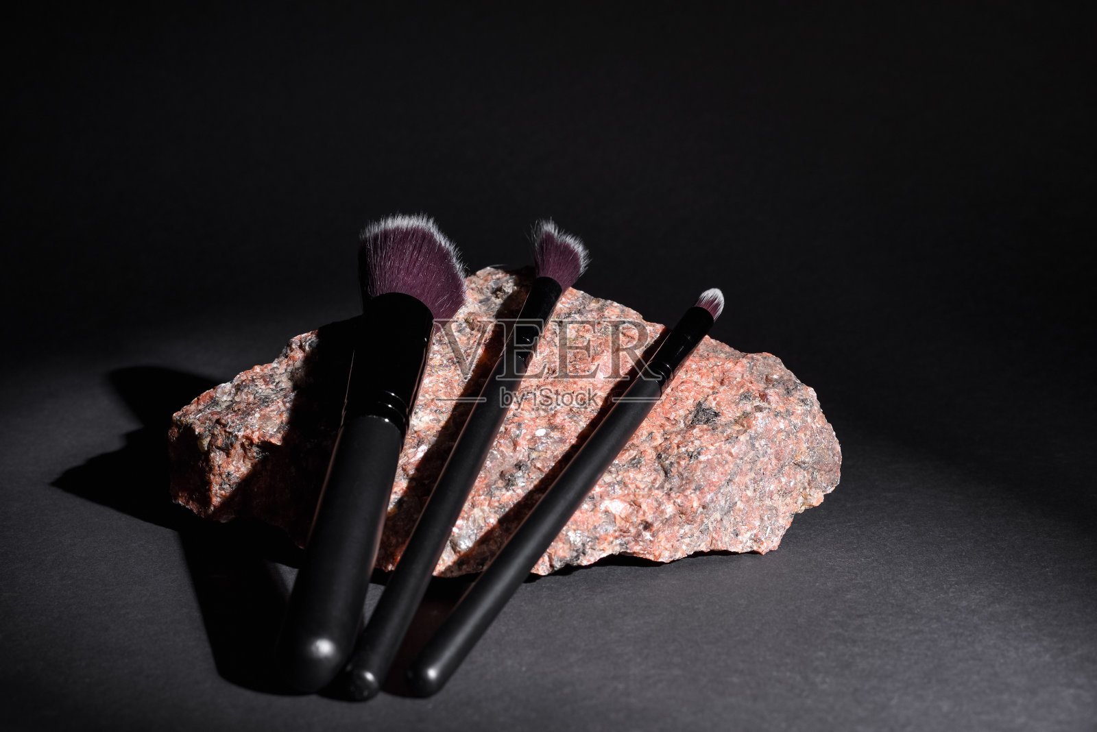 化妆刷躺在黑色背景的花岗岩上。为化妆师设置不同的化妆刷。照片摄影图片