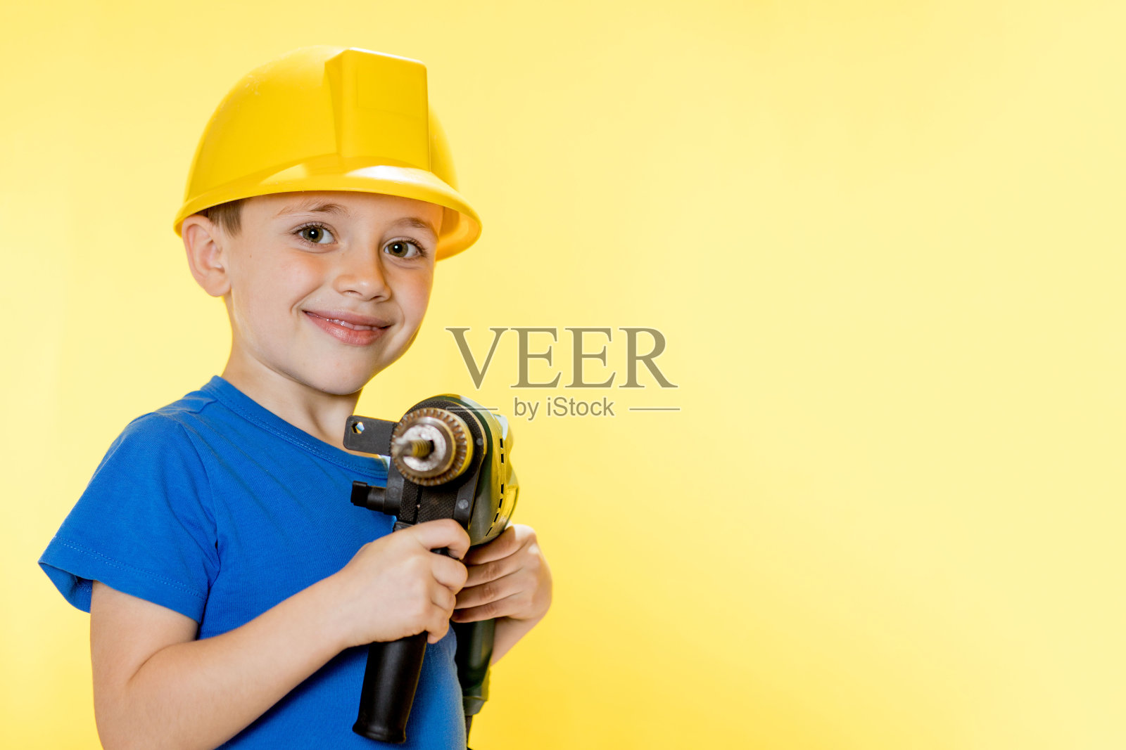 穿着蓝色衬衫,面带微笑,手里拿着钻头的建筑工人照片摄影图片