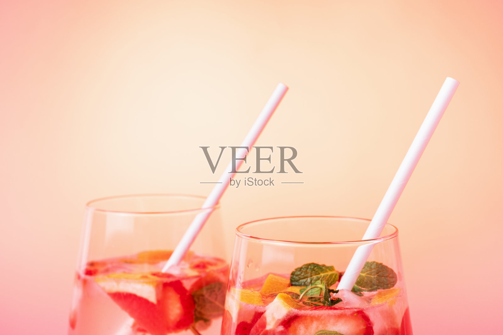 两杯冰茶,草莓和葡萄柚片,正面。照片摄影图片