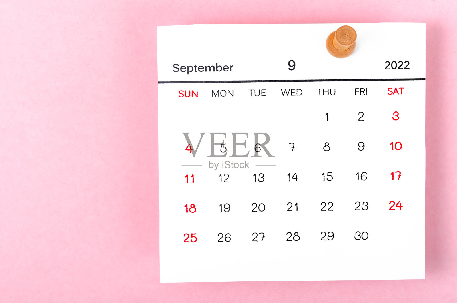 2022年9月挂历和粉红色背景上的木制推杆。照片摄影图片