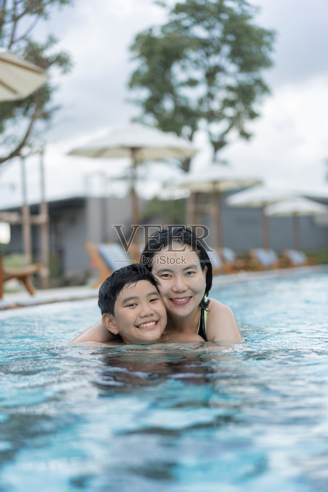 亚洲家庭,年幼的男孩和40多岁的母亲在游泳池玩得很开心照片摄影图片