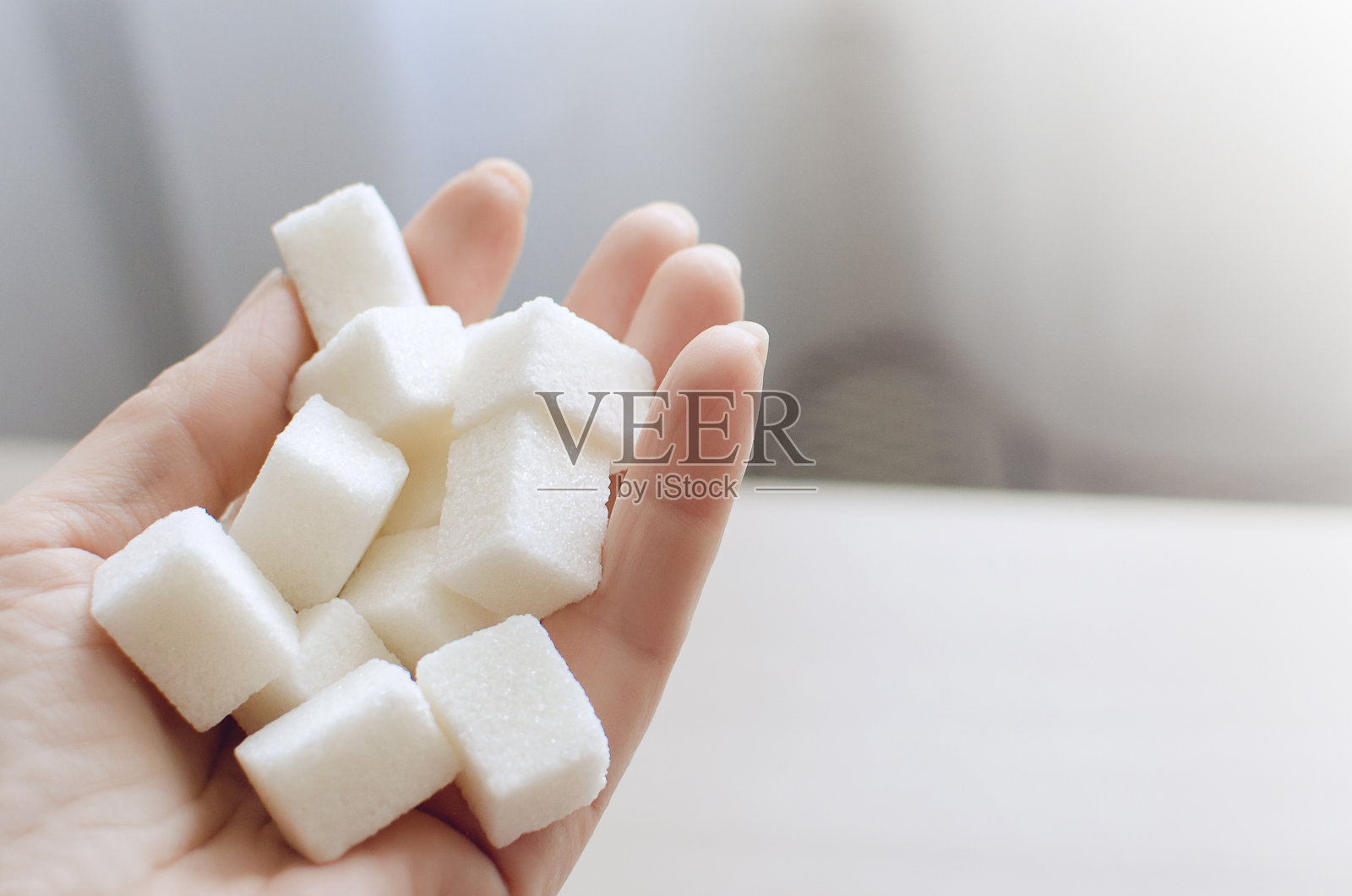 白糖块在手里。不健康饮食的概念。照片摄影图片