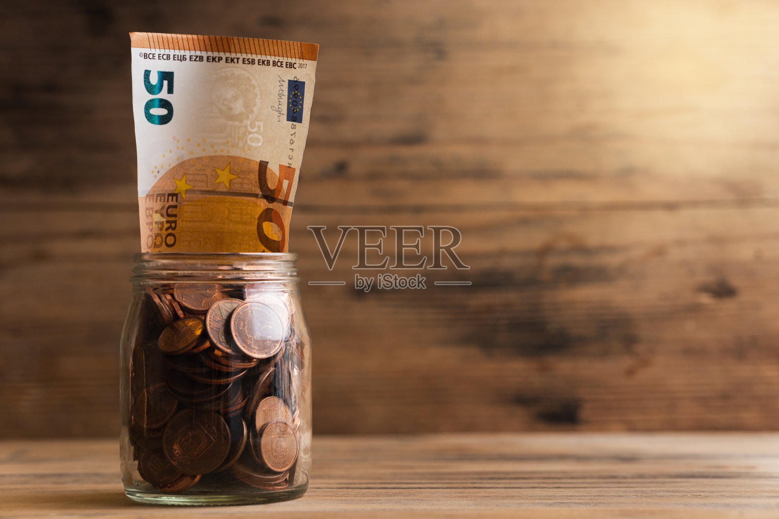 50欧元的钞票,装在一个装满铜币的玻璃罐里。照片摄影图片