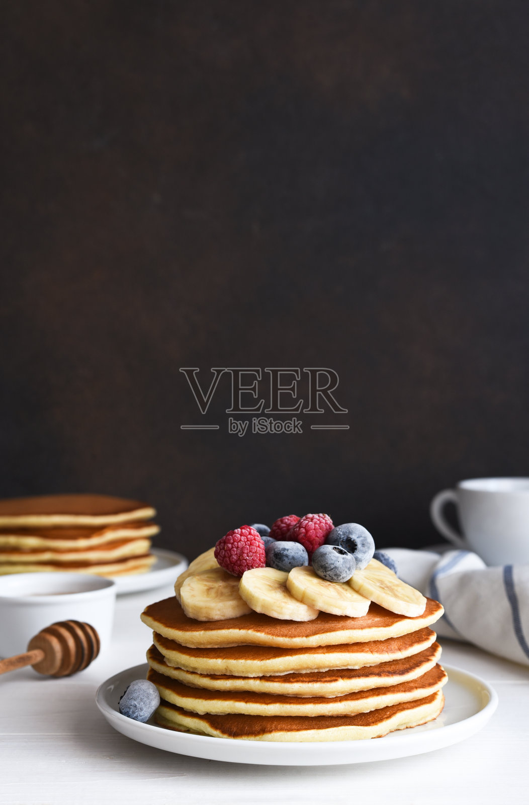 厨房桌上的早餐是一堆煎饼、浆果和糖浆。早上好照片摄影图片