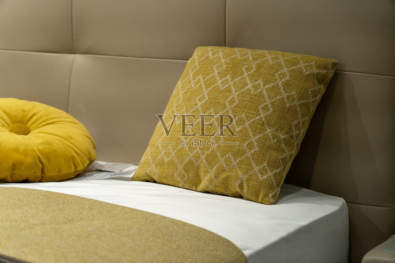 新米色毯子的特写与装饰黄色枕头,皮革床头板在卧室在酒店或斯堪的纳维亚风格的公寓样品模型照片摄影图片