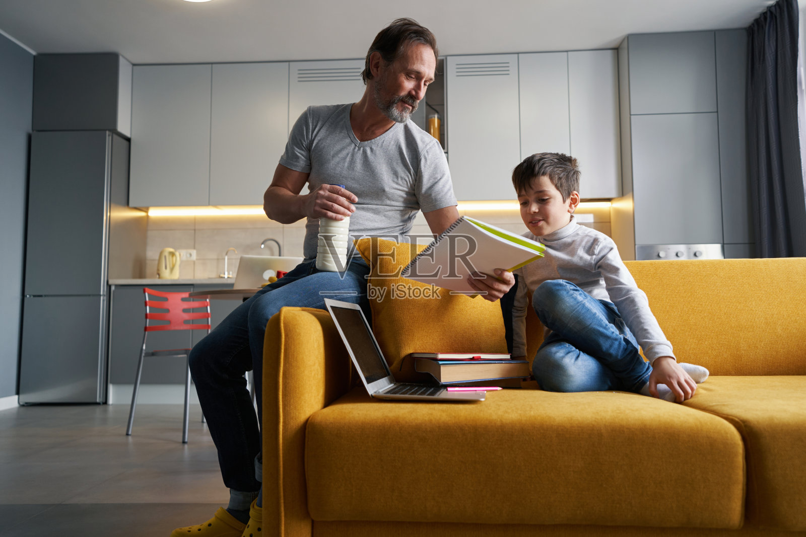 男人向儿子解释他在家庭作业中的错误照片摄影图片