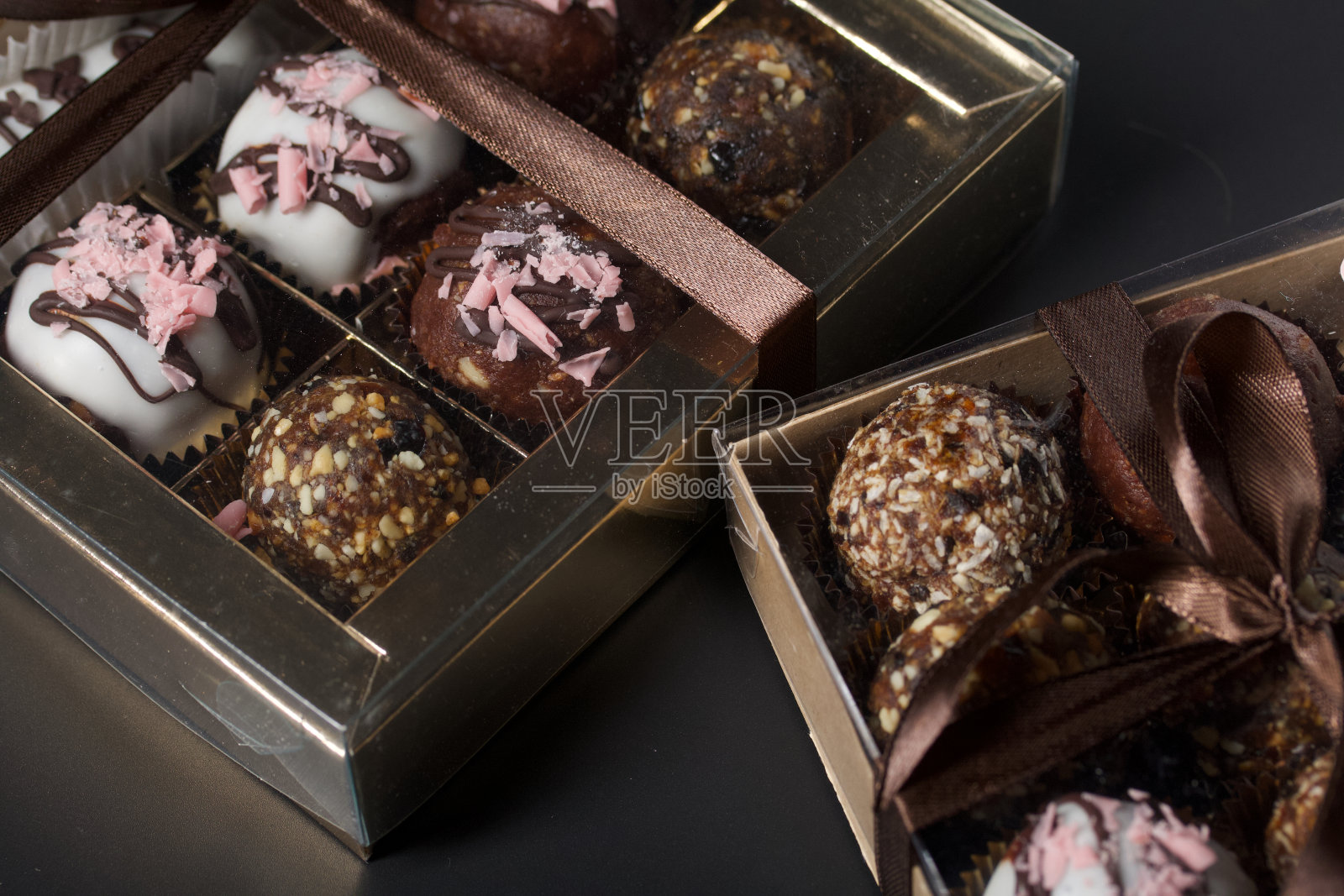巧克力糖。在礼品盒里。用丝带系成一个蝴蝶结。在黑色的背景上。照片摄影图片