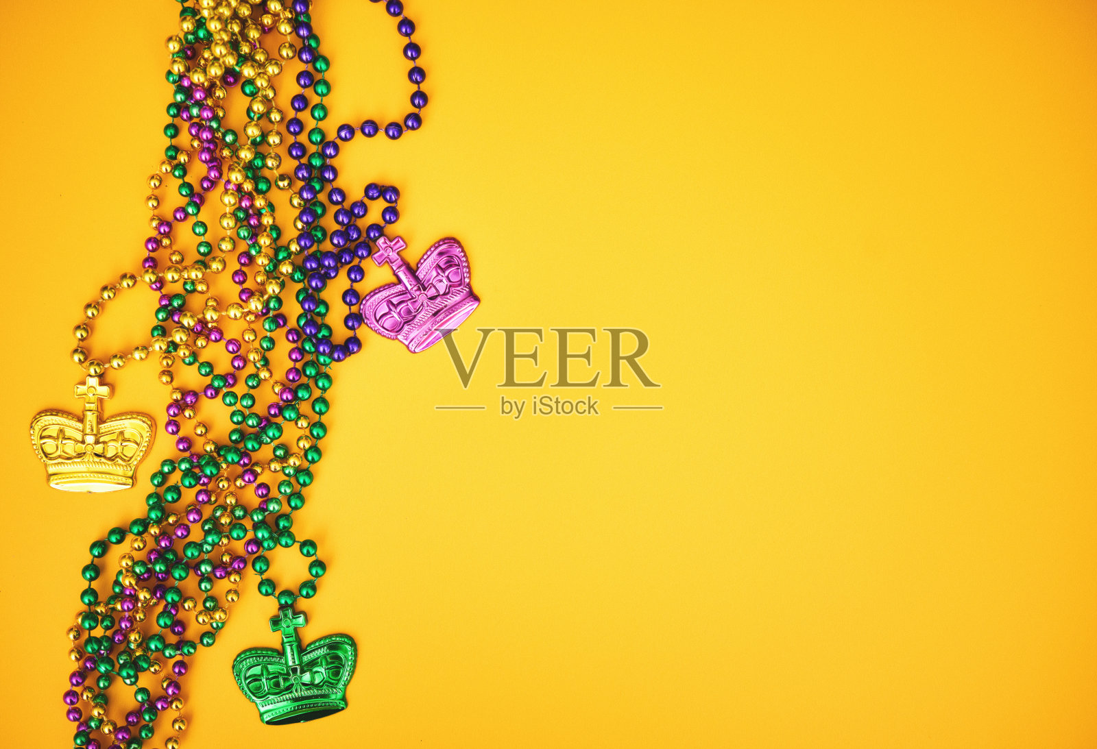 黄色的背景上点缀着彩色的珠子和皇冠照片摄影图片