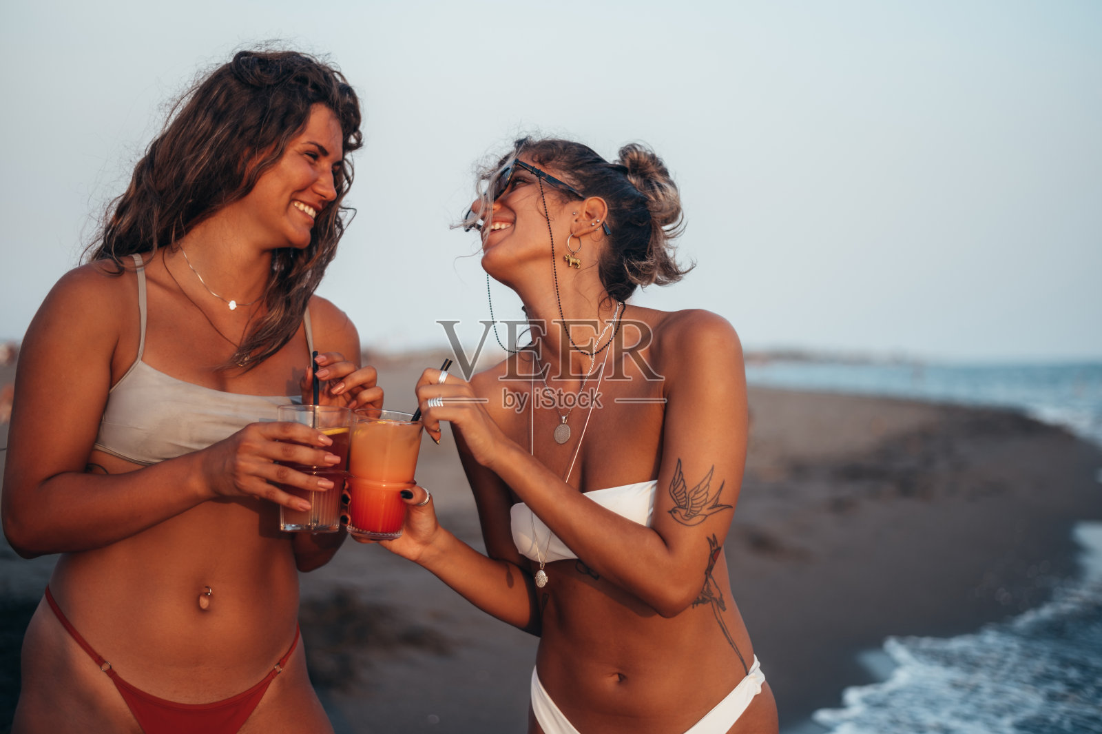 有魅力的朋友一起在海滩上享受假期,喝鸡尾酒照片摄影图片