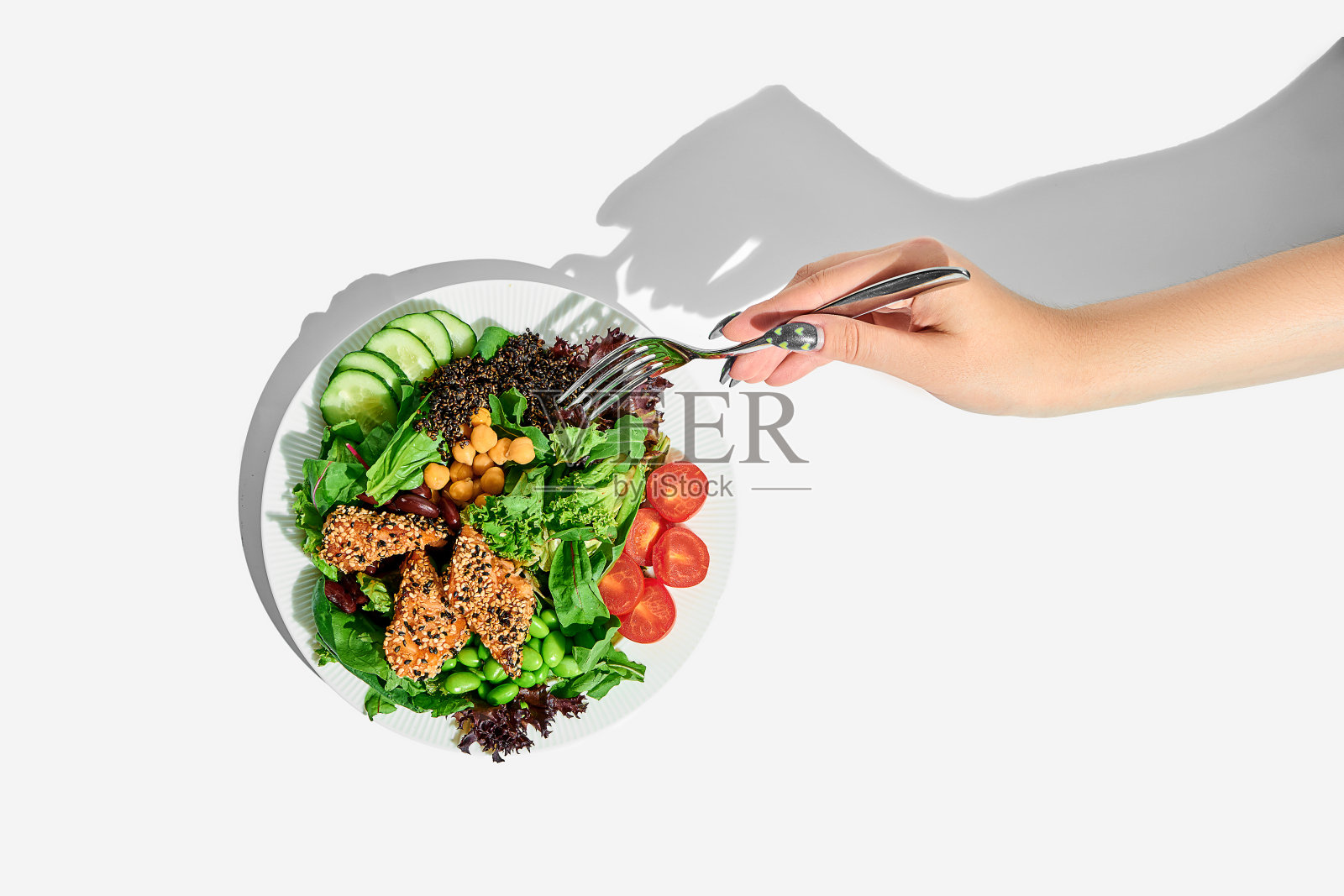 一位女士的手伸向白色背景上的鲑鱼鹰嘴豆沙拉。健康食品的海报照片摄影图片