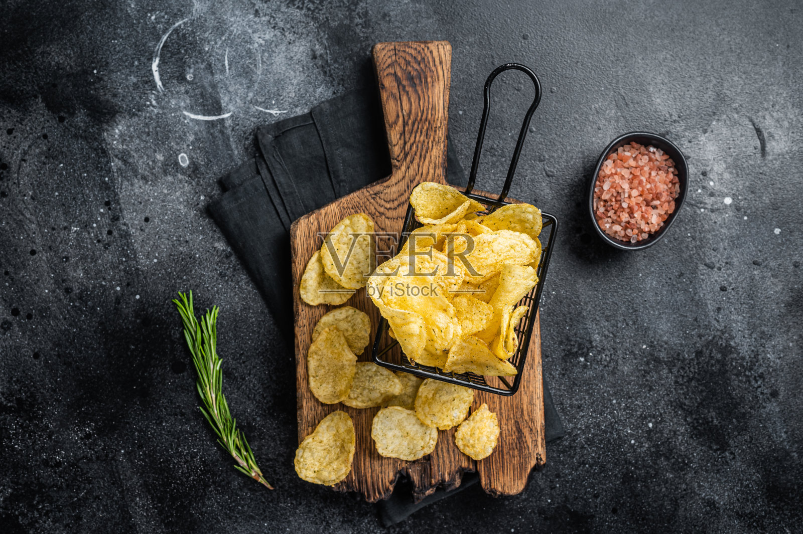 篮子里的海盐迷迭香薯片。黑暗的背景。俯视图照片摄影图片