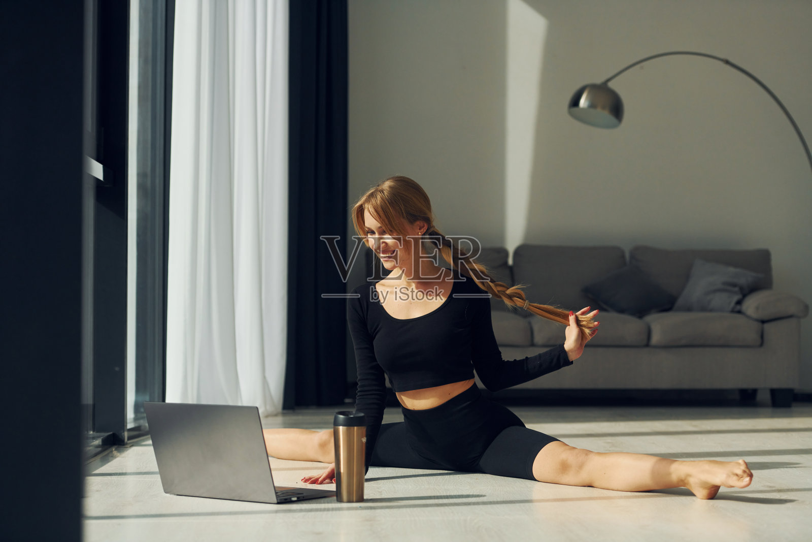 使用笔记本电脑。穿着运动服的女人在室内做瑜伽照片摄影图片