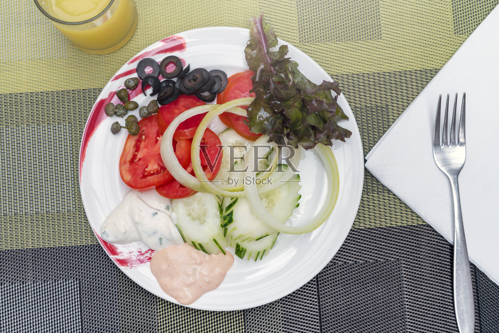 一盘沙拉,切碎的洋葱,黄瓜和西红柿,一些橄榄,生菜叶在桌子上的一个盘子和一个叉子。健康的素食早餐,平坦的生活方式照片摄影图片