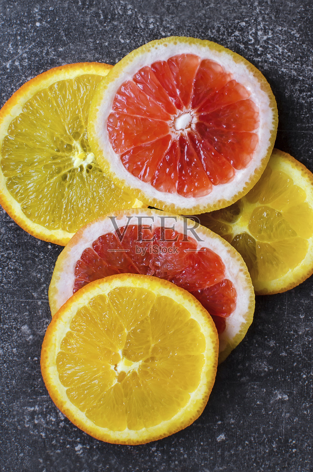 切成薄片的柑橘水果片在深色的年份背景上。橙子和葡萄柚,特写,垂直摄影。照片摄影图片