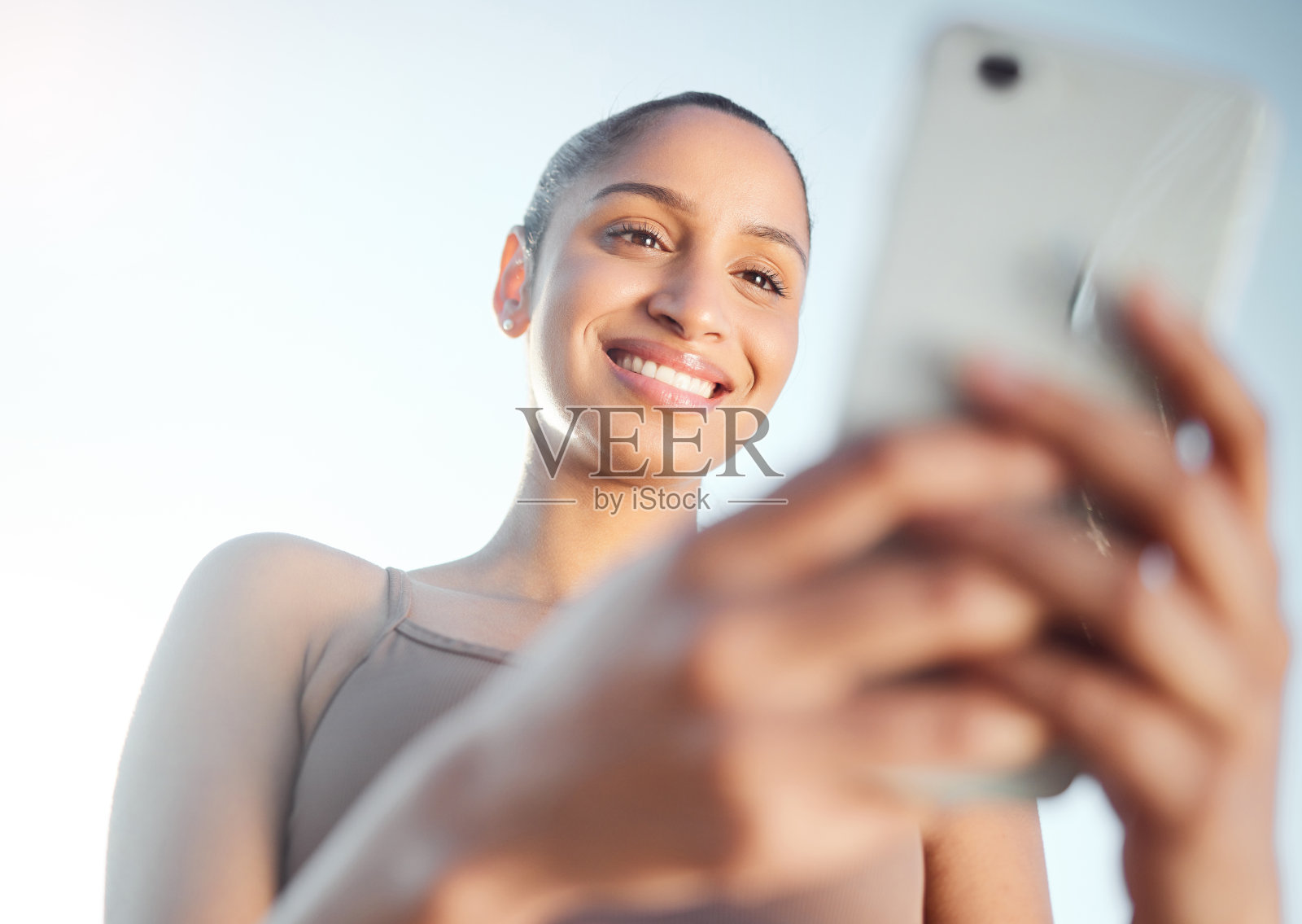 低角度拍摄的运动年轻女子在户外运动时使用手机照片摄影图片