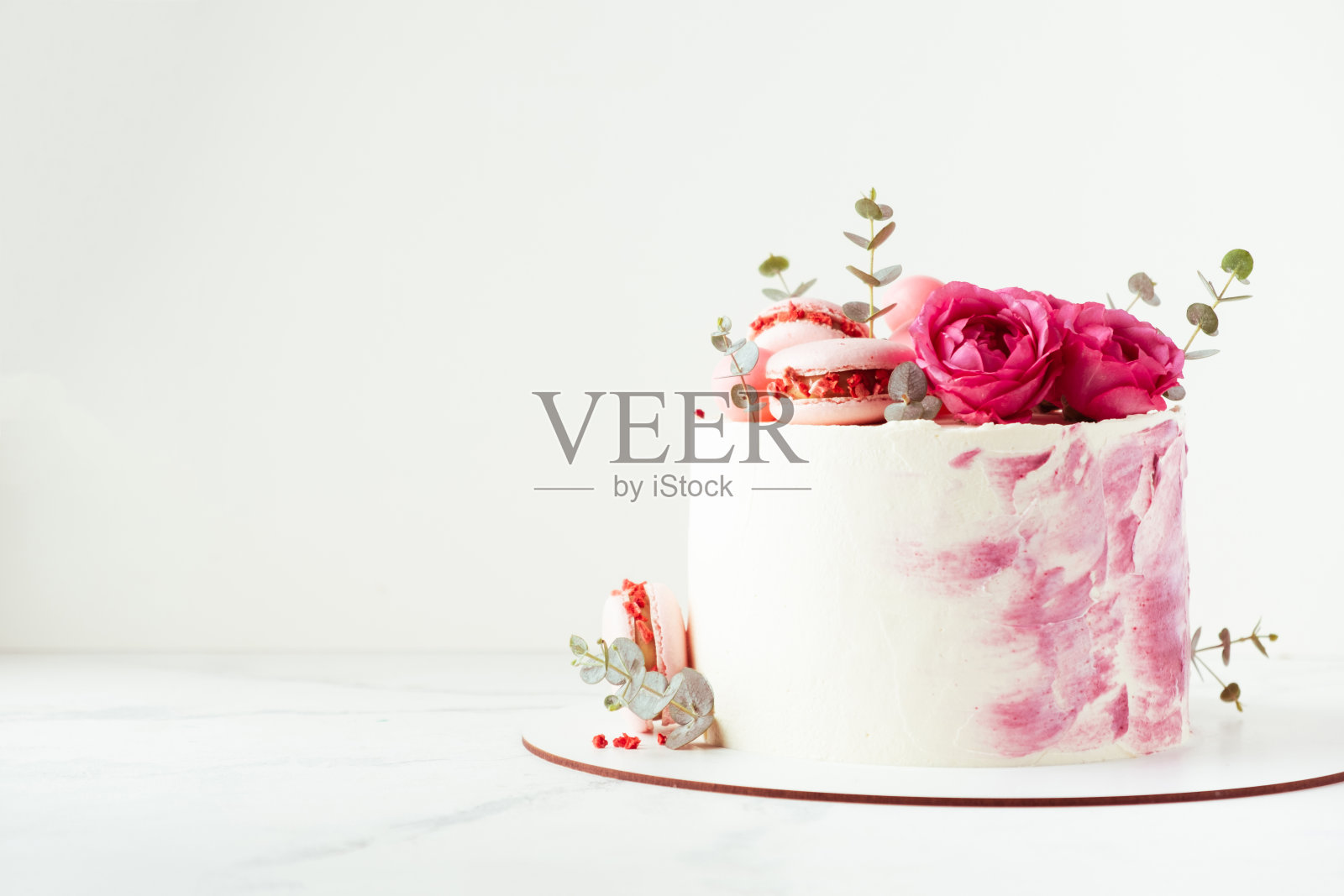 美丽的生日蛋糕,粉色奶油芝士糖霜装饰着马卡龙和玫瑰。情人节快乐。照片摄影图片