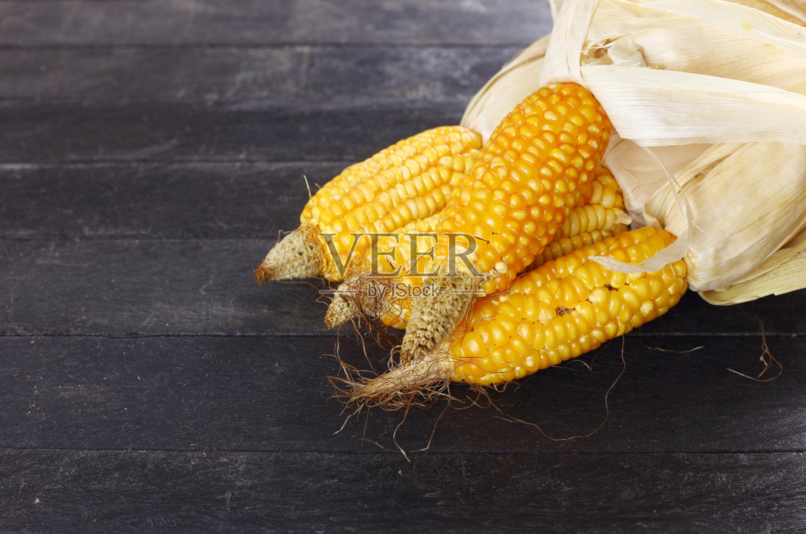 黑色桌子上带有干叶的成熟黄色玉米,用于播种 - 有机概念照片摄影图片
