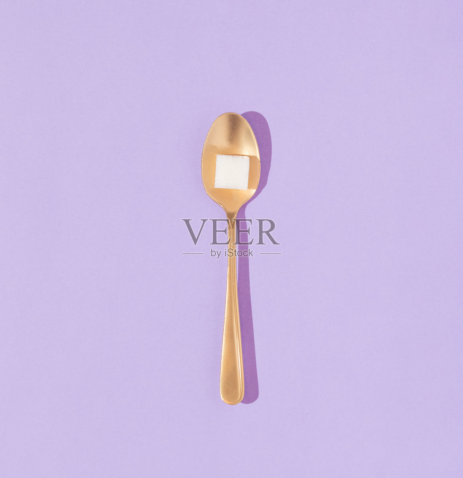创意概念与糖方和金色汤匙在柔和的紫色背景。最小平。八九十年代的复古美食美学风格。照片摄影图片