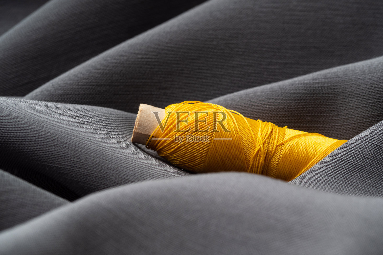 卷轴与灰色丝绸织物上的黄色线程,宏观,纹理,特写。豪华亮丽的缝纫背景。裁剪,工作室的概念。高级时装,天然面料照片摄影图片