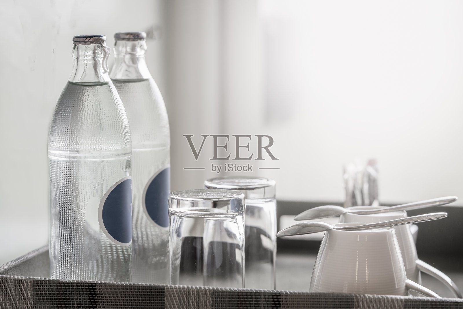 酒店房间里有两瓶矿泉水,托盘上还有干净的玻璃杯照片摄影图片