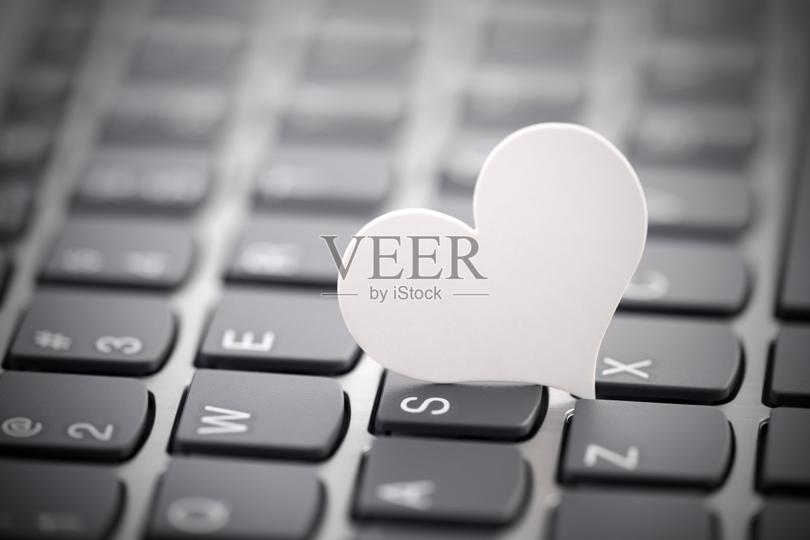 电脑键盘上的小白纸心。网络交友的概念。照片摄影图片