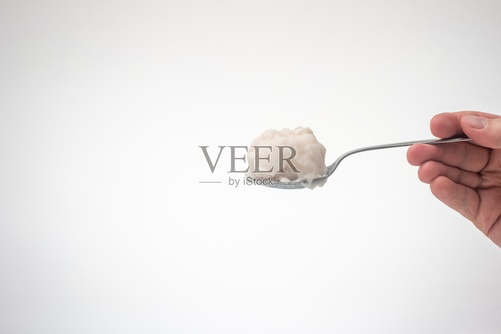 白种人男性用手拿着金属勺子,勺子上放着猪油或猪油。近景摄影,孤立在白色背景上照片摄影图片