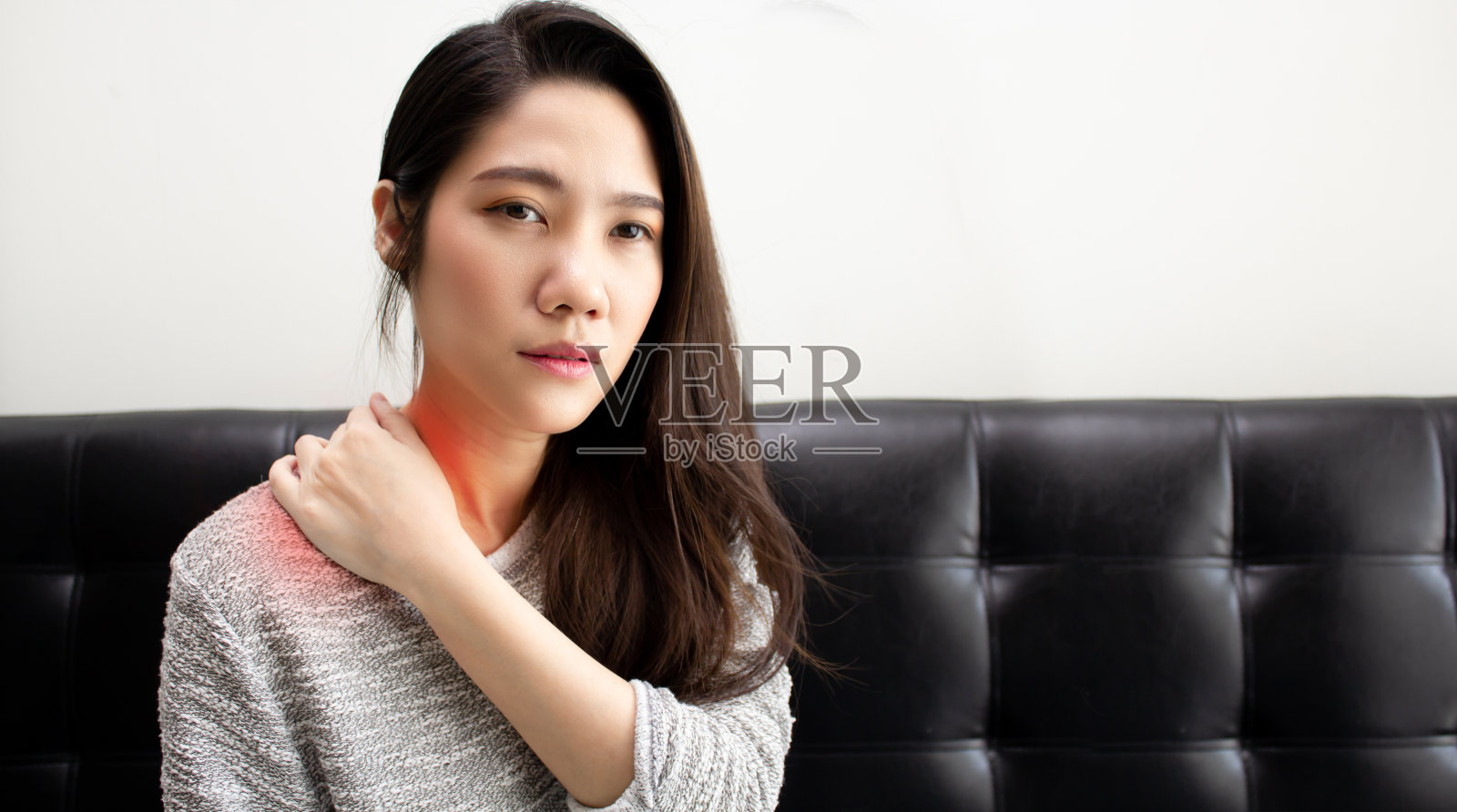 亚洲妇女坐在客厅里用手触摸自己的脖子,感觉压力和疼痛,因为不好的人体工程学和伤害照片摄影图片