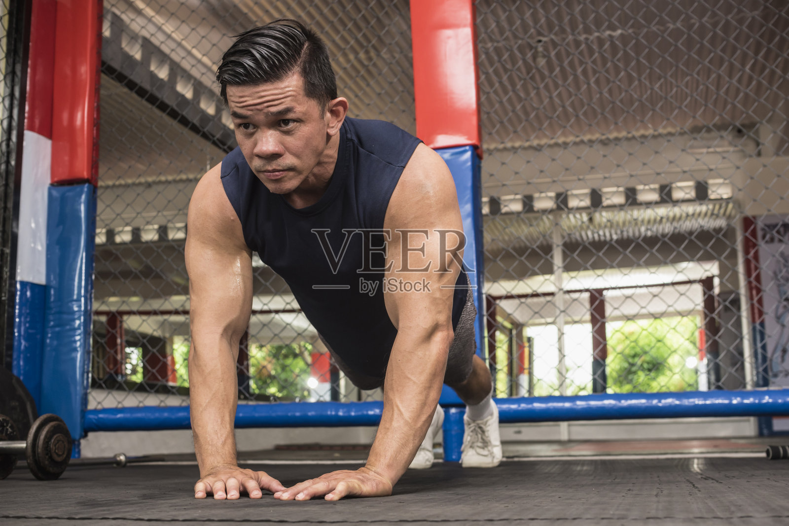一个健康的亚洲男子在综合格斗馆做钻石形俯卧撑。体重健美操或HIIT锻炼。锻炼胸部、腹肌和三头肌。照片摄影图片