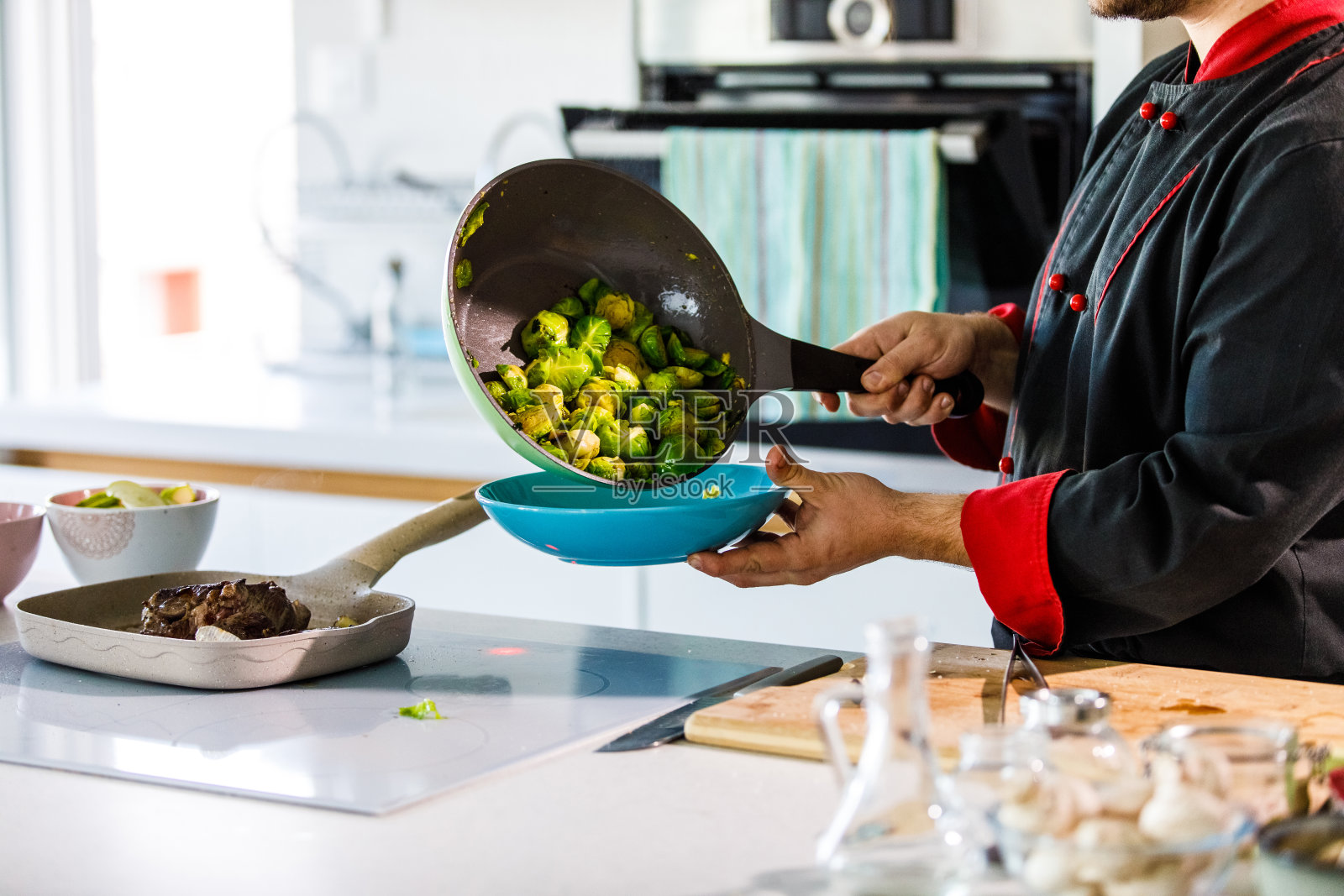 专业厨师将sautéed布鲁塞尔喷口倒在盘子上照片摄影图片