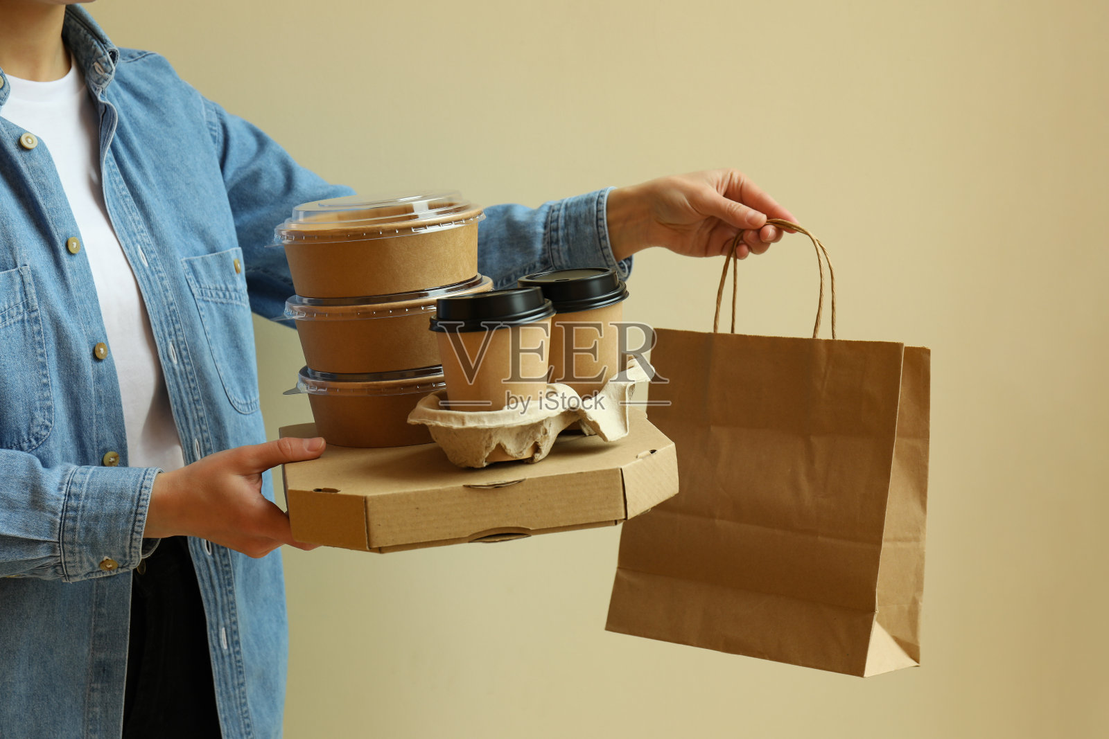 米色背景下,女人拿着外卖食品的容器照片摄影图片