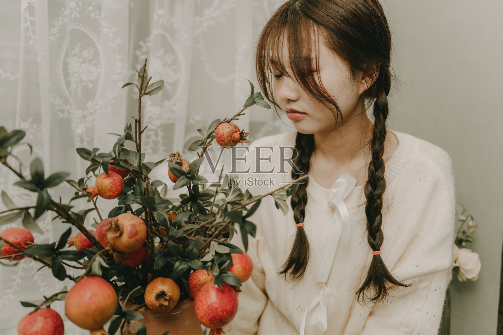 一个美丽的亚洲女孩坐在窗边看花照片摄影图片