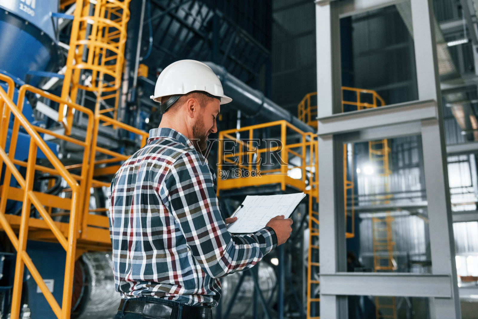 戴着白色安全帽。穿制服的建筑工人在工厂里照片摄影图片