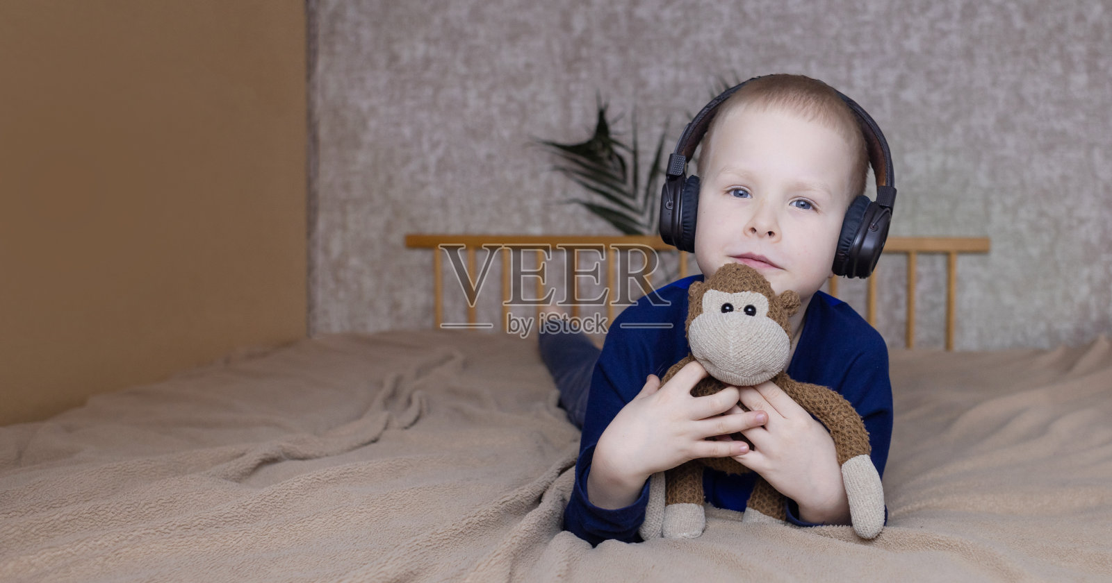 男孩戴着耳机在睡觉前听孩子们的冥想。健康的儿童神经系统概念。睡前放松。金发男人在家里放松。听力治疗照片摄影图片