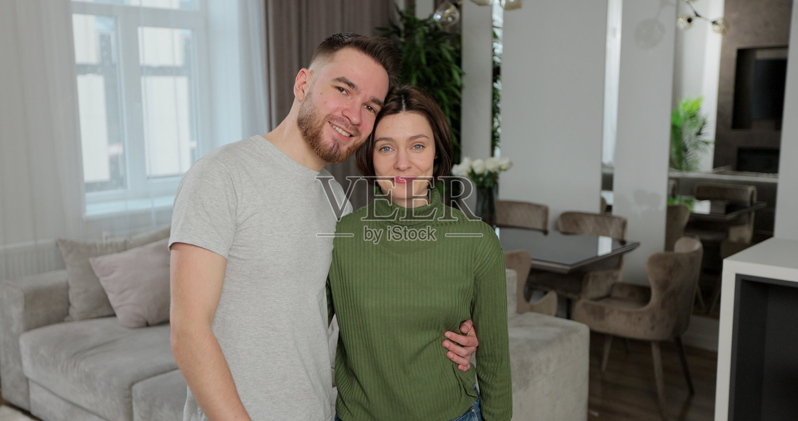 幸福的年轻夫妇看着相机,展示钥匙组成的新公寓。感到兴奋或购买自己的房子或搬进出租公寓。房地产的概念。照片摄影图片