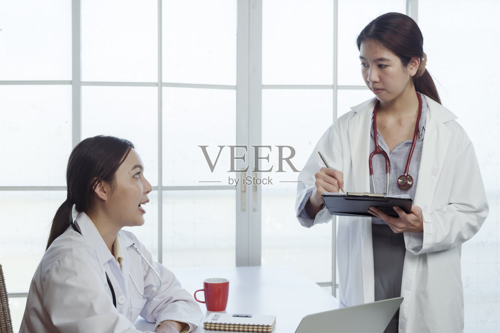 4k的时候,一名身穿白衬衫的亚裔女医学院学生向她征求建议。在医院的办公室里谈论病人的病情和医生的老师照片摄影图片