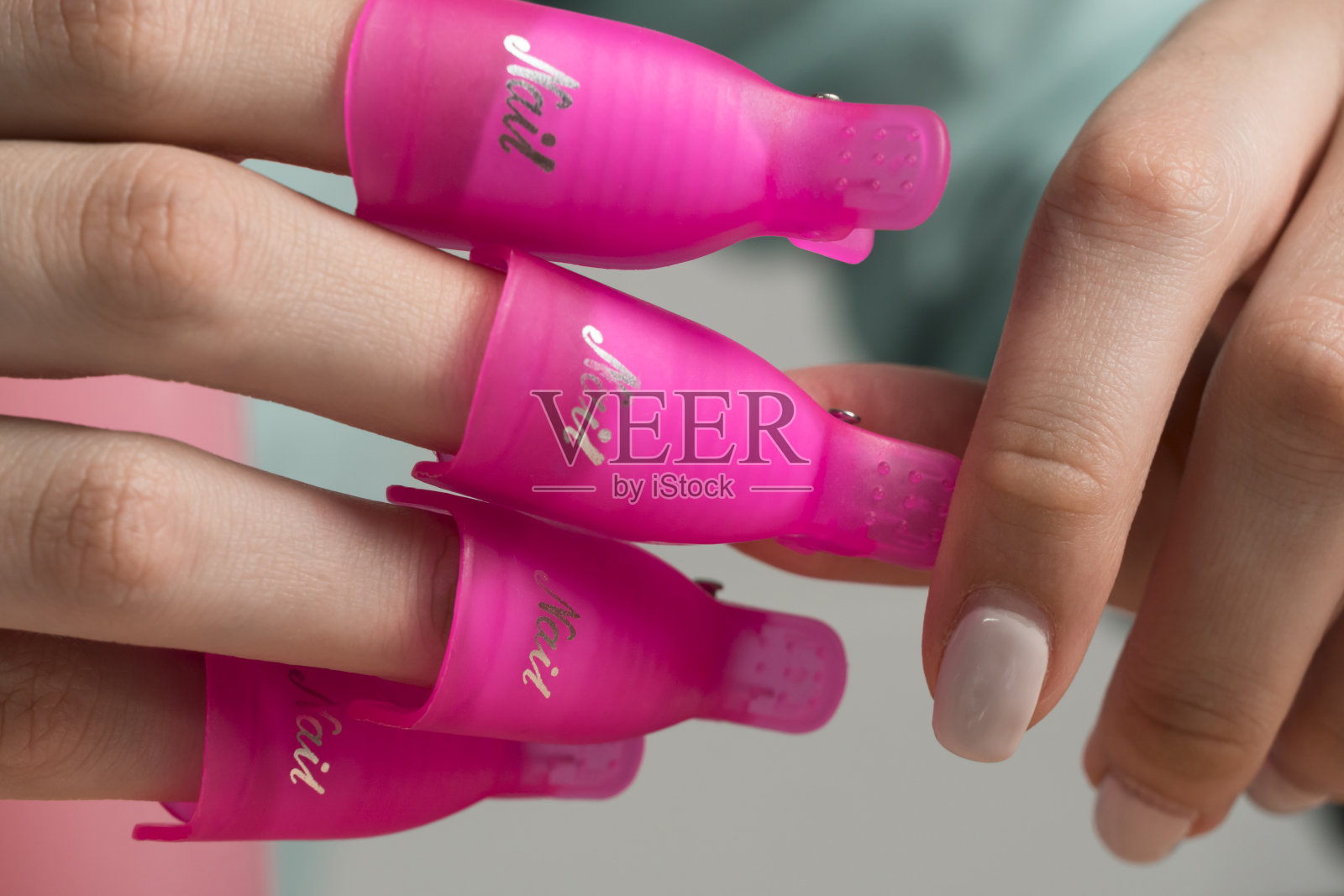 用指甲夹去掉旧的指甲油凝胶。这个女孩自己修指甲。美丽、卫生程序。指甲夹,家庭自我护理。旧的美甲,破旧的指甲油。照片摄影图片