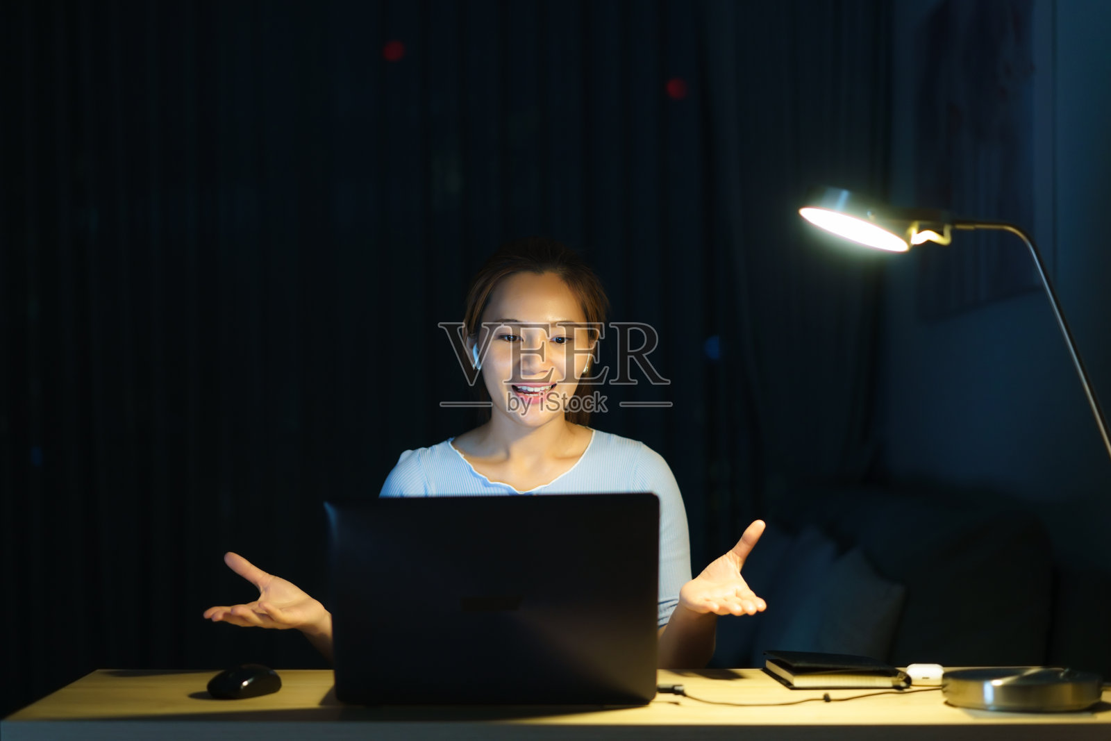 在家工作的亚洲女性是晚上在家里通过视频电话与同事或经理一起工作。照片摄影图片