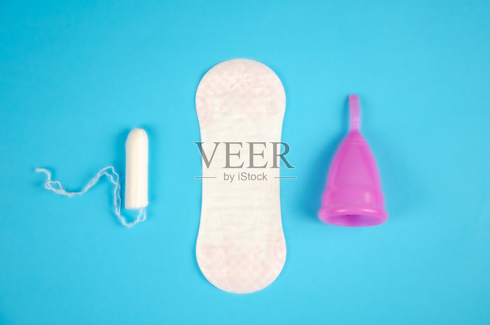蓝色背景的月经杯,一次性卫生巾和卫生棉条。可重复使用的月经杯,环保。照片摄影图片