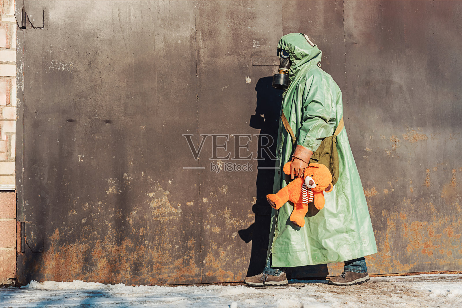 穿着防辐射服,带着防毒面具的人,带着玩具熊照片摄影图片