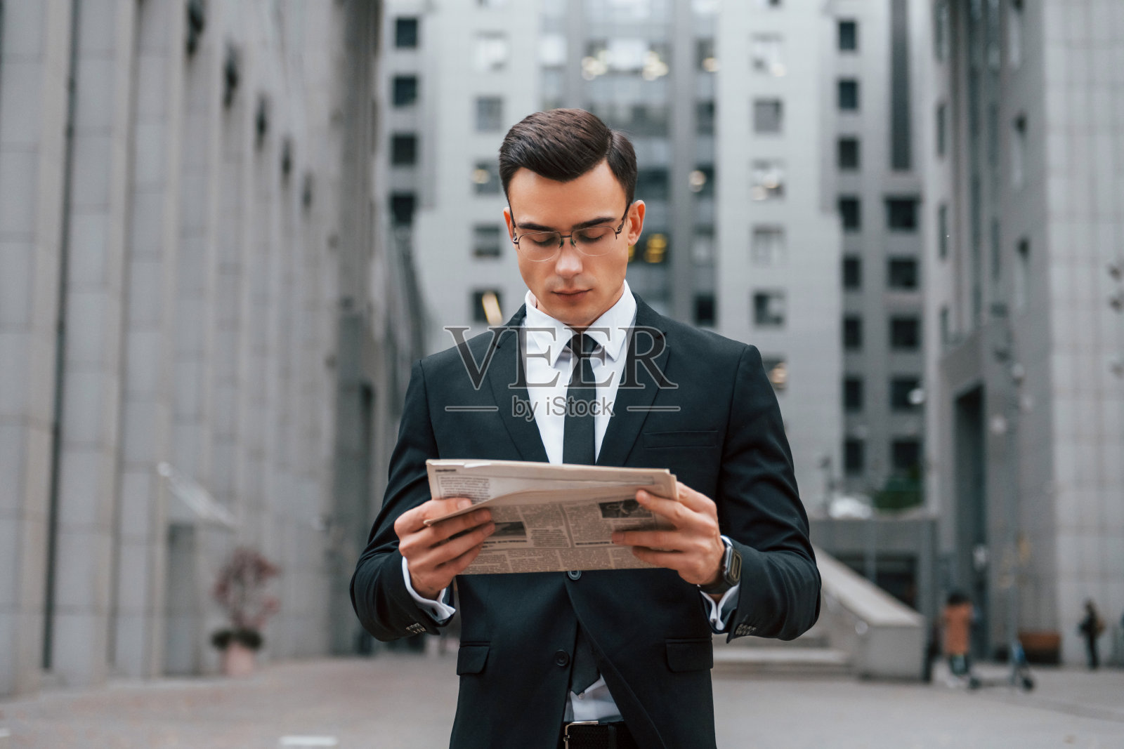 阅读一些新闻。身着黑色西装打领带的商人正在城市的户外活动照片摄影图片