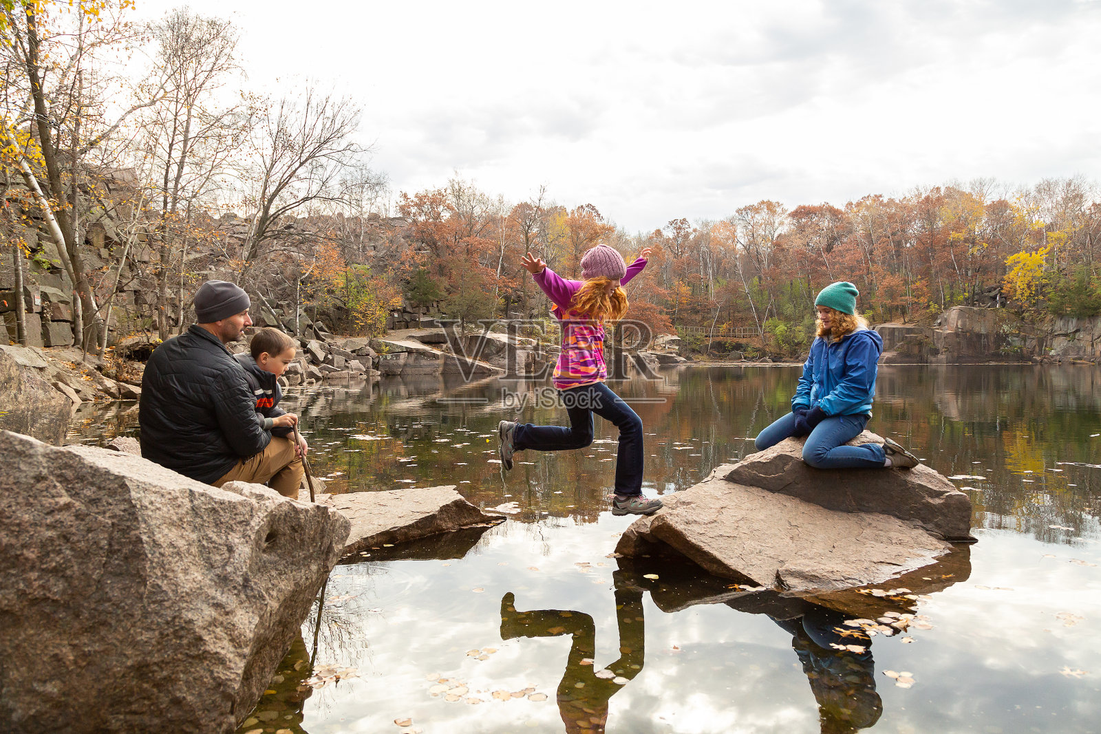 女孩在湖上的岩石间跳跃照片摄影图片