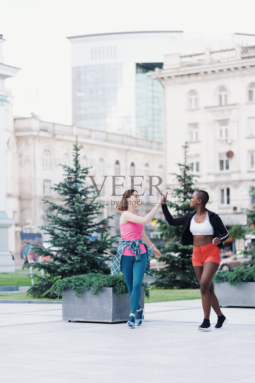 两个多民族女孩跑过城市的街道,在户外交流。照片摄影图片